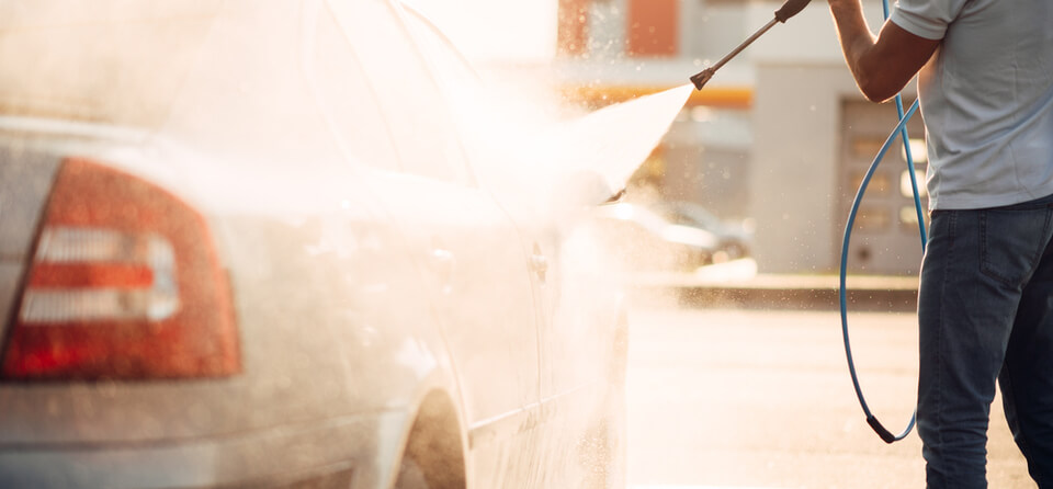 Medewerker maakt auto schoon in wasstraat